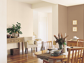Neutral brown traditional dining setting with wooden floorboards and dining table and chairs plant